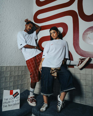 Two people posing against a wall with a red and white abstract design.