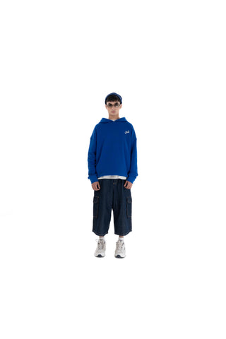 Person wearing a blue hoodie and dark pants on a white background