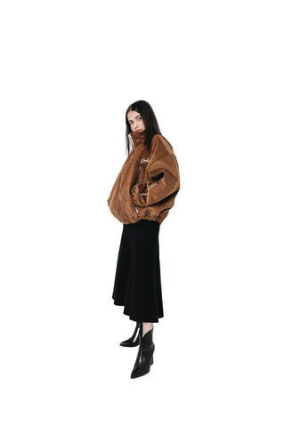 Person wearing a brown jacket and black skirt on a white background